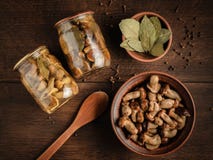 Cogumelos postos de conserva da floresta em uns frascos e em uma bacia fotografia de stock Cogumelos postos de conserva da floresta em uns frascos e em uma bacia fotografia de stock
