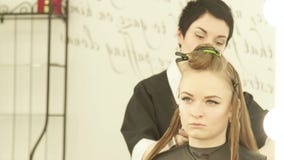 Coiffeur féminin à l'aide de la bride pour les cheveux de réparation pendant la coiffure dans le salon de beauté Fermez-vous vers banque de vidéos Coiffeur féminin à l'aide de la bride pour les cheveux de réparation pendant la coiffure dans le salon de beauté Fermez-vous vers banque de vidéos