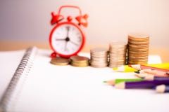 Coins stack and red alarm clock with Colored pencils on notebook. stock photography Coins stack and red alarm clock with Colored pencils on notebook. stock photography