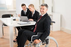 Colegas de On Wheelchair With del hombre de negocios en oficina foto de archivo Colegas de On Wheelchair With del hombre de negocios en oficina foto de archivo