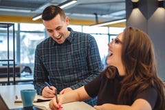Colegas masculinos e fêmeas que riem do escritório imagem de stock Colegas masculinos e fêmeas que riem do escritório imagem de stock