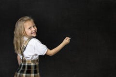 Colegiala menor dulce joven con la escritura feliz sonriente del pelo rubio con tiza en pizarra Imágenes de archivo libres de regalías Colegiala menor dulce joven con la escritura feliz sonriente del pelo rubio con tiza en pizarra Imágenes de archivo libres de regalías