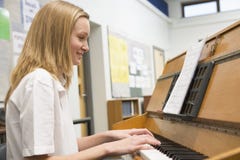 Colegiala que juega el piano en clase de música imágenes de archivo libres de regalías Colegiala que juega el piano en clase de música imágenes de archivo libres de regalías