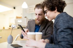 Colleagues analyzing information on smartphone in cafe stock images Colleagues analyzing information on smartphone in cafe stock images