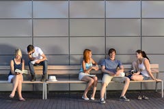 College students sitting on bench modern wall