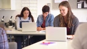 High school students studying together on laptop in class