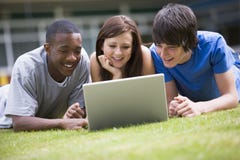 College students using laptop on campus lawn