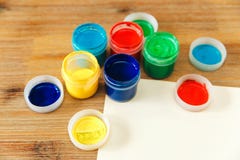 Colored cans with paint and paper.wooden table. stock photography Colored cans with paint and paper.wooden table. stock photography