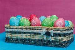 Colored Easter eggs in a basket on a blue-pink background. Stock Photo Colored Easter eggs in a basket on a blue-pink background. Stock Photo