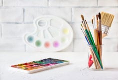 Colorful dry watercolor tablet set and white plastic palette and paint brushes and pencils on white texture background royalty free stock photography Colorful dry watercolor tablet set and white plastic palette and paint brushes and pencils on white texture background royalty free stock photography