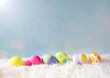 Colorful Happy Easter Eggs in Snow against Blue Sky with sunlight with room or space for copy, text, or your words. Horizontal