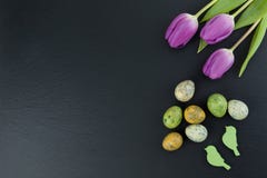 Colorful quail eggs and tulip flowers and green wooden birds on stone table. Top view with copy space stock photos Colorful quail eggs and tulip flowers and green wooden birds on stone table. Top view with copy space stock photos