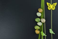 Colorful quail eggs and yellow butterfly and green wooden birds on stone table. Top view with copy space stock photos Colorful quail eggs and yellow butterfly and green wooden birds on stone table. Top view with copy space stock photos