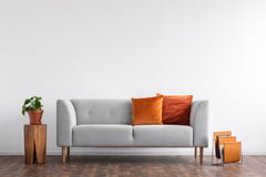 Comfortable couch with orange and red pillow in spacious living room interior,