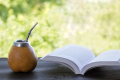 Compagnon de Yerba dans le matero de courge avec le livre ouvert sur la table en bois photo stock Compagnon de Yerba dans le matero de courge avec le livre ouvert sur la table en bois photo stock