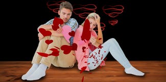 Composite image of attractive young couple sitting holding two halves of broken heart Stock Image Composite image of attractive young couple sitting holding two halves of broken heart Stock Image