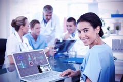 Composite image of beautiful smiling doctor typing on keyboard with her team behind stock photo Composite image of beautiful smiling doctor typing on keyboard with her team behind stock photo