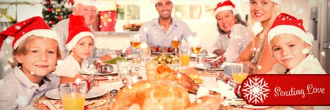 Composite image of happy family wearing santa hats around the dinner table stock photo Composite image of happy family wearing santa hats around the dinner table stock photo