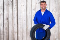 Composite image of mechanic holding tire on white background Royalty Free Stock Photos Composite image of mechanic holding tire on white background Royalty Free Stock Photos