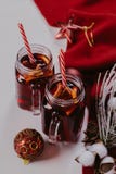 Composição decorada das canecas com vinho ferventado com especiarias no lenço feito malha, fim acima imagem de stock Composição decorada das canecas com vinho ferventado com especiarias no lenço feito malha, fim acima imagem de stock