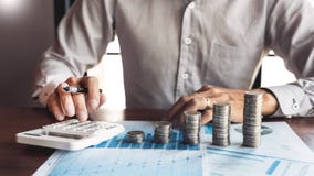 Comptable Calculating d'homme d'affaires sur les documents de donn?es et la pile de pile de pi?ces de monnaie, l'investissement d photo stock Comptable Calculating d'homme d'affaires sur les documents de donn?es et la pile de pile de pi?ces de monnaie, l'investissement d photo stock