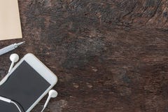 Computer portatile, smartphone, nota in calce, matita e trasduttore auricolare di vista superiore su vecchio fondo di legno con l fotografia stock Computer portatile, smartphone, nota in calce, matita e trasduttore auricolare di vista superiore su vecchio fondo di legno con l fotografia stock