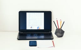 Computer portatile, smartphone, taccuino e matite in supporto concreto sulla tavola bianca nel fondo di affari dell'ufficio per l fotografie stock Computer portatile, smartphone, taccuino e matite in supporto concreto sulla tavola bianca nel fondo di affari dell'ufficio per l fotografie stock