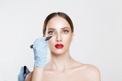 Conceito da cirurgia plástica Medique marcas do desenho de Hands na cara fêmea contra o fundo cinzento branco Tratamento facial O foto de stock royalty free Conceito da cirurgia plástica Medique marcas do desenho de Hands na cara fêmea contra o fundo cinzento branco Tratamento facial O foto de stock royalty free