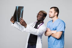 Conceito dos cuidados médicos, o médico e da radiologia - dois doutores que olham o raio X no fundo cinzento fotografia de stock royalty free Conceito dos cuidados médicos, o médico e da radiologia - dois doutores que olham o raio X no fundo cinzento fotografia de stock royalty free