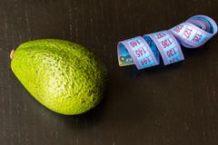 Conceito saudável do estilo de vida, abacate e fita de medição no fundo preto fotos de stock Conceito saudável do estilo de vida, abacate e fita de medição no fundo preto fotos de stock