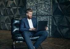 Concentraiting sul progetto Giovane uomo moderno premuroso che per mezzo del computer mentre sedendosi al suo posto di lavoro immagine stock libera da diritti Concentraiting sul progetto Giovane uomo moderno premuroso che per mezzo del computer mentre sedendosi al suo posto di lavoro immagine stock libera da diritti