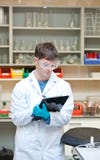 Concentrated male scientist writing on a clipboard stock photo Concentrated male scientist writing on a clipboard stock photo