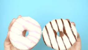 Concept choice between chocolate donut and strawberry donut. female hands with red nail polish hold pink and brown donut stock video Concept choice between chocolate donut and strawberry donut. female hands with red nail polish hold pink and brown donut stock video