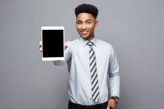 Concept d'affaires - homme d'affaires professionnel bel heureux d'afro-américain montrant le comprimé numérique au client photos libres de droits Concept d'affaires - homme d'affaires professionnel bel heureux d'afro-américain montrant le comprimé numérique au client photos libres de droits