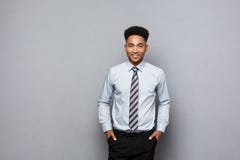 Concept d'affaires - homme d'affaires professionnel sûr heureux d'afro-américain posant au-dessus du fond gris image stock Concept d'affaires - homme d'affaires professionnel sûr heureux d'afro-américain posant au-dessus du fond gris image stock