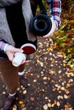concept d'envie de voyager et de voyage Femme versant une boisson chaude dans la tasse du thermos Thé potable dehors images stock concept d'envie de voyager et de voyage Femme versant une boisson chaude dans la tasse du thermos Thé potable dehors images stock
