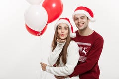 Concept de Noël - la jeune amie tenant le ballon est étreignante et jouante avec son ami faisant une surprise dessus photographie stock libre de droits Concept de Noël - la jeune amie tenant le ballon est étreignante et jouante avec son ami faisant une surprise dessus photographie stock libre de droits