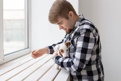 Concept de personnes et d'animal familier - homme heureux tenant un chien Jack Russell Terrier au-dessus de fond de fenêtre photographie stock Concept de personnes et d'animal familier - homme heureux tenant un chien Jack Russell Terrier au-dessus de fond de fenêtre photographie stock