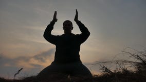 Concept de religion La silhouette d'un moine masculin s'est engag?e dans la m?ditation ? la lumi?re du soleil de coucher du solei banque de vidéos Concept de religion La silhouette d'un moine masculin s'est engag?e dans la m?ditation ? la lumi?re du soleil de coucher du solei banque de vidéos