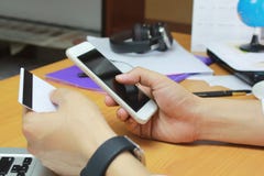 Concept en ligne d'achats Homme utilisant le téléphone intelligent mobile et carte de crédit sur la table dans le bureau photographie stock Concept en ligne d'achats Homme utilisant le téléphone intelligent mobile et carte de crédit sur la table dans le bureau photographie stock