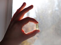 Vitamin D or omega 3 capsules. Vitamin gel in hand against the window. The concept of a lack of vitamin D in the body stock photo Vitamin D or omega 3 capsules. Vitamin gel in hand against the window. The concept of a lack of vitamin D in the body stock photo