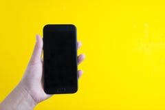 Concept moderne de media : remettez tenir un smartphone moderne au-dessus de fond coloré jaune avec l'espace de copie Smartphone photo libre de droits Concept moderne de media : remettez tenir un smartphone moderne au-dessus de fond coloré jaune avec l'espace de copie Smartphone photo libre de droits