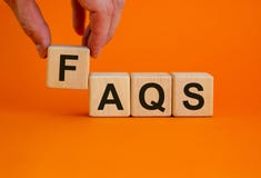 Concept word `FAQS` on cubes on a beautiful orange background. Male hand. Business concept. Copy space