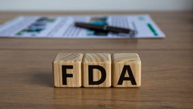 Concept word FDA on cubes on a beautiful wooden table, pen and document. Business concept