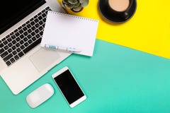 Conception ?tendue plate de bureau de travail avec le carnet, le smartphone et le cactus de labtop sur le fond vert et jaune photos stock Conception ?tendue plate de bureau de travail avec le carnet, le smartphone et le cactus de labtop sur le fond vert et jaune photos stock