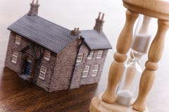 Concepto de las propiedades inmobiliarias del reloj de arena y de la casa foto de archivo libre de regalías Concepto de las propiedades inmobiliarias del reloj de arena y de la casa foto de archivo libre de regalías