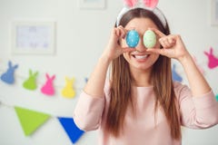 Concepto del celbration de pascua de la mujer joven en casa en los oídos de un conejito que sostienen los huevos que cubren ojos imagen de archivo libre de regalías Concepto del celbration de pascua de la mujer joven en casa en los oídos de un conejito que sostienen los huevos que cubren ojos imagen de archivo libre de regalías