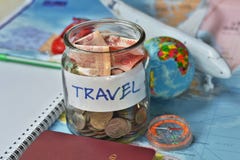 Concepto del presupuesto de viaje los ahorros del dinero del viaje en un tarro de cristal con el compás, el pasaporte y los avion fotografía de archivo libre de regalías Concepto del presupuesto de viaje los ahorros del dinero del viaje en un tarro de cristal con el compás, el pasaporte y los avion fotografía de archivo libre de regalías