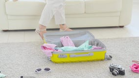 Concepto del viaje y de las vacaciones La mujer joven feliz est? embalando la ropa colorida del verano en la maleta del equipaje almacen de video Concepto del viaje y de las vacaciones La mujer joven feliz est? embalando la ropa colorida del verano en la maleta del equipaje almacen de video
