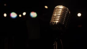 Concert vintage metal microphone on stage in empty retro club. Spotlights.